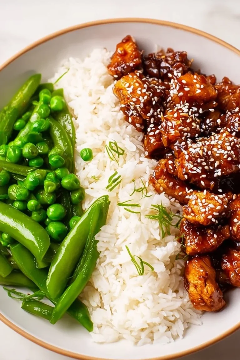 A plate of Asian High Protein Sesame Chicken garnished with sesame seeds and green onions